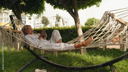 girl resting on a hammock with a tablet in hand on a forest background. High quality 4k footage