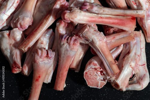 A pile of raw goat bones and cartilage, showcasing their fresh and natural state. Ideal for visuals related to culinary preparation, butchery, or food industry themes. photo