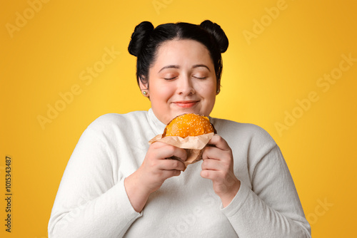 Cuadro en lienzo Plump Hungry Girl Holding Burger In Hands And Sniffing It With Pleased Face Expr