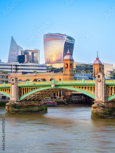 A vibrant cityscape of London featuring modern skyscrapers along the River Thames, reflecting the warm glow of sunset. photo