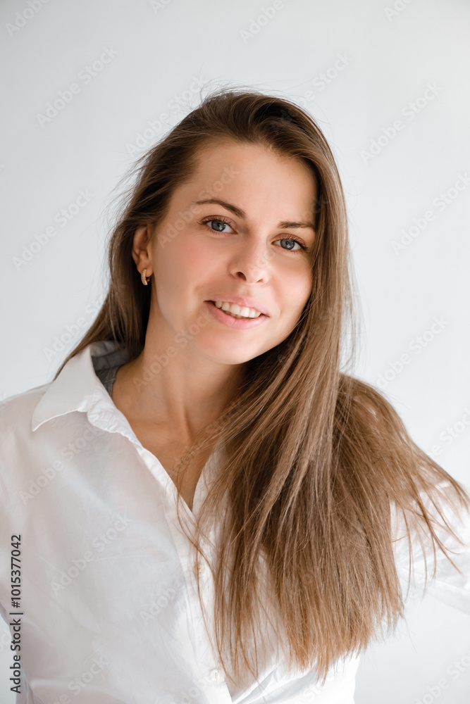Young smiling confident business woman wearing white top shirt casual clothes looking camera isolated on grey background studio portrait. Vertical shot. Lifestyle concept. Professional office worker Young smiling confident business woman wearing white top shirt casual clothes looking camera isolated on grey background studio portrait. Vertical shot. Lifestyle concept. Professional office worker