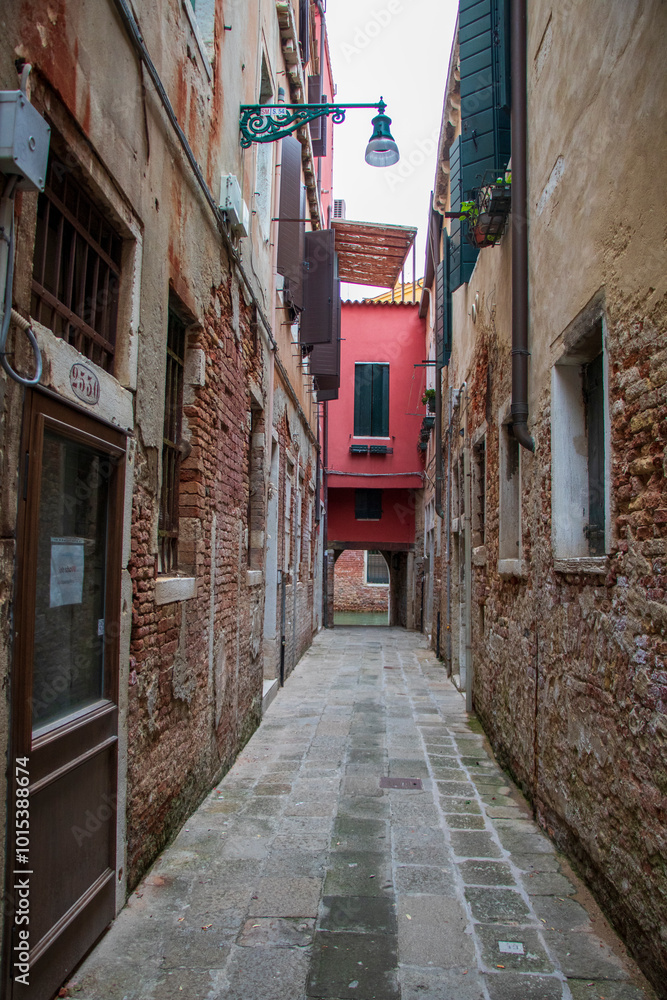 Fototapeta premium narrow street in the old town in Venice, Italy with red house 