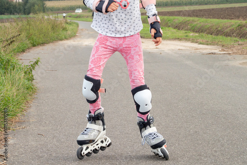 A girl rollerskates on a country road, wearing protective gear for safety.