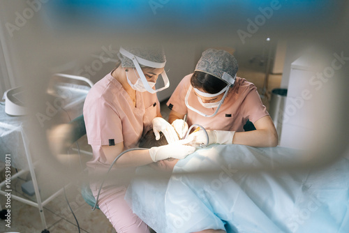 High-angle view of two trichologist specialist collecting hair follicles from back of head of male patient for hair transplantation in clinic. Process of hair transplant with FUE Sapphire method. photo