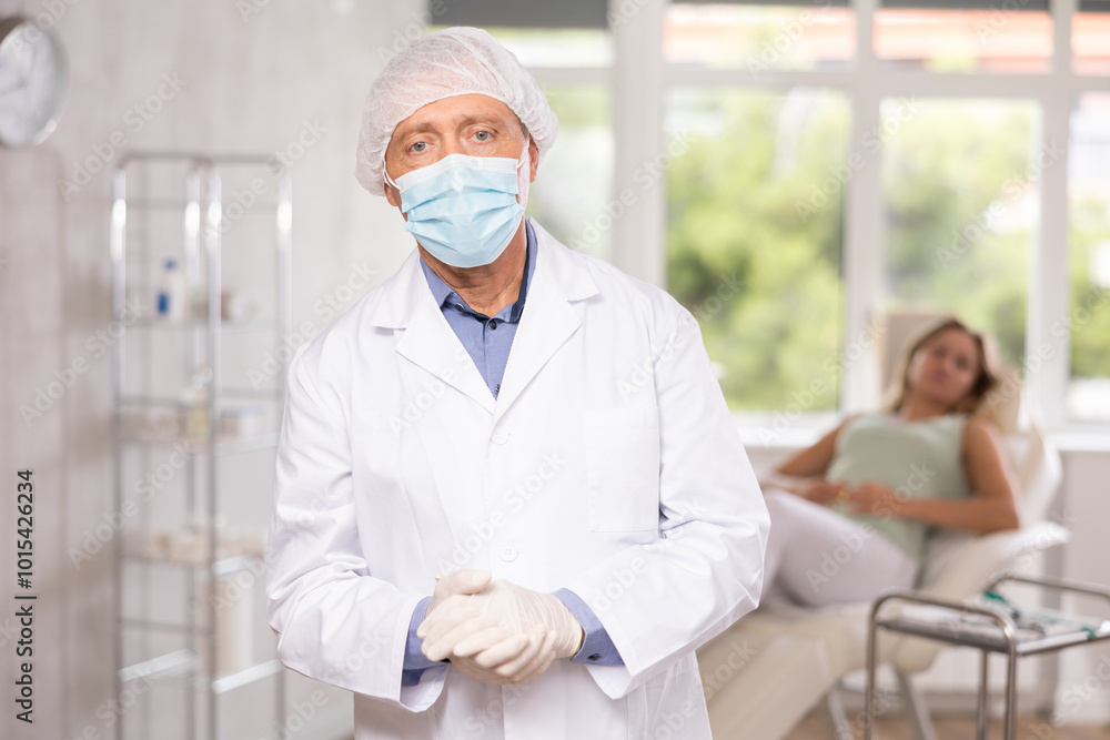 Obraz premium Smiling aged man dermatologist standing in light cosmetology cabinet with wide windows