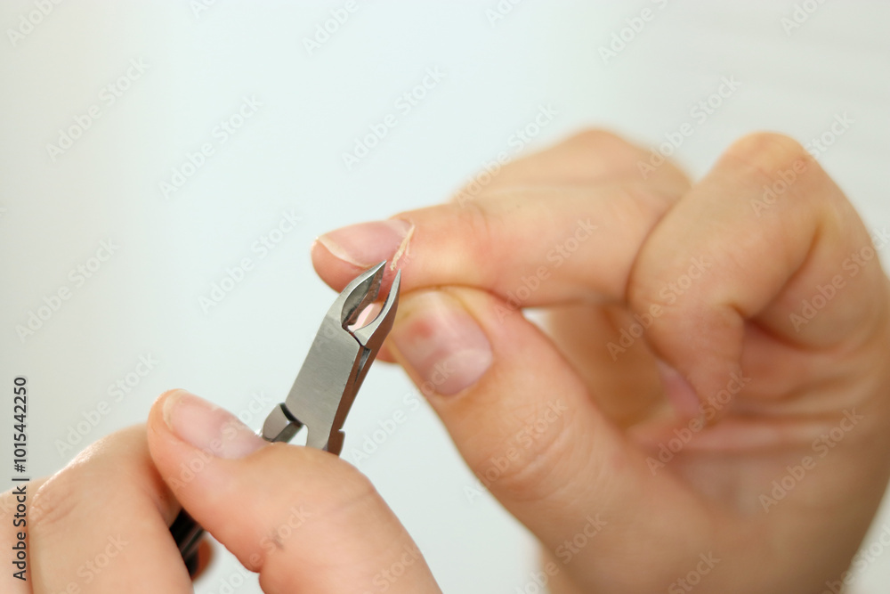 Close up of woman removing cuticles from fingers with tweezers, natural manicure Close up of woman removing cuticles from fingers with tweezers, natural manicure