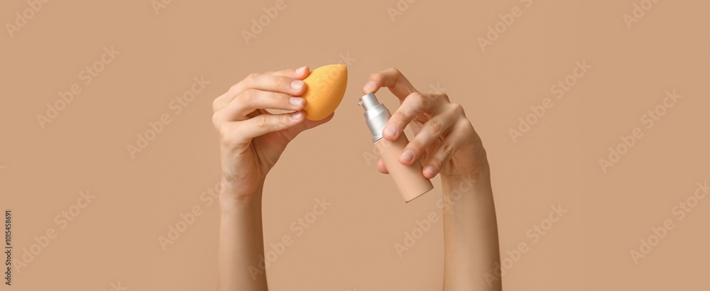 Female hands with makeup foundation and sponge on brown background Female hands with makeup foundation and sponge on brown background