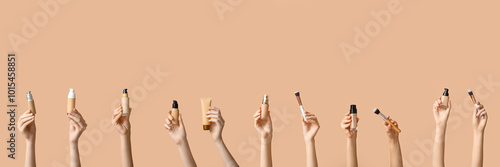 Female hands with bottles and tube of makeup foundation on brown background photo