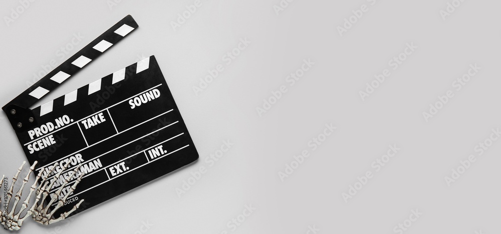 Naklejka premium Clapperboard with skeleton hands on grey background with space for text