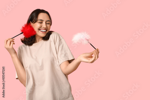 Quadro su tela Joyful young woman laughing with eyes closed holding red and pink feather tickle