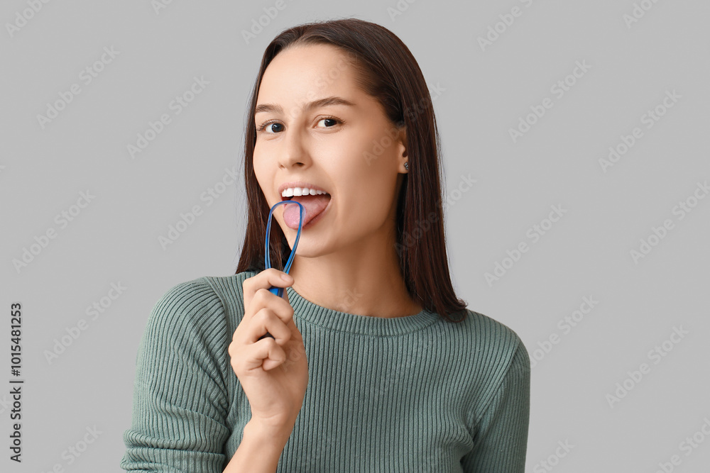 Beautiful young woman with tongue scraper on grey background Beautiful young woman with tongue scraper on grey background
