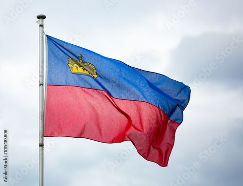 Liechtenstein national flag flying on flagstaff in background of grey cloudy sky photo