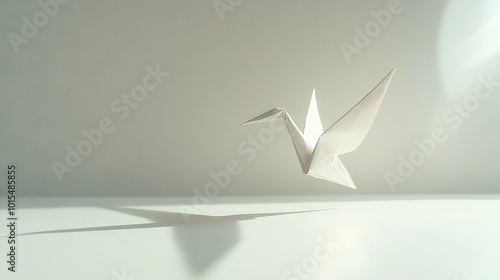 White origami bird flying, shadow on floor; white wall background