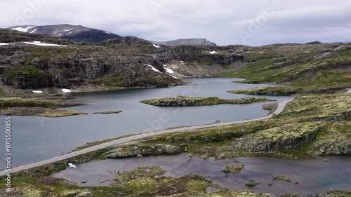 Car driving throught Norvegian severe Tundra nature with birdsyey top view Picturesque northern lakes Norwagian landscape and modern highway construction aerial 4K video. Rondane National Park, Norway photo