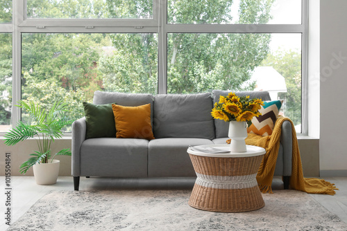 Interior of living room with grey sofa and sunflowers on coffee table photo