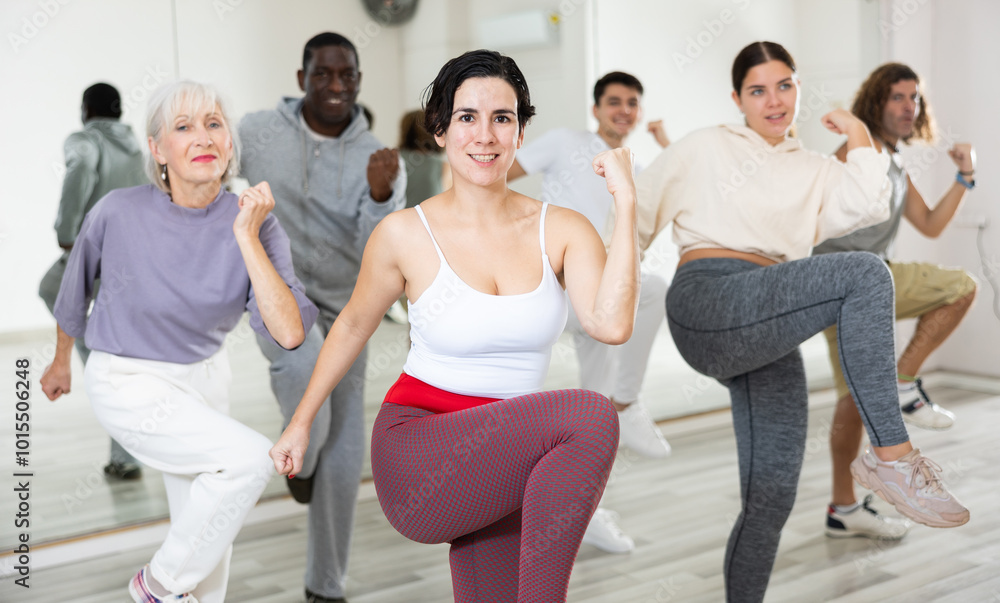 Fototapeta premium Positive sporty young Hispanic woman practicing modern vigorous dance movements in group dance class