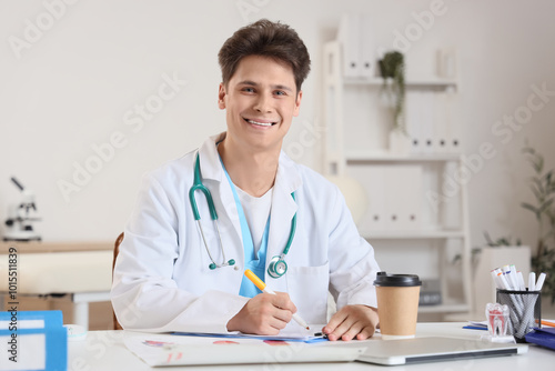 Male medical intern at table in clinic