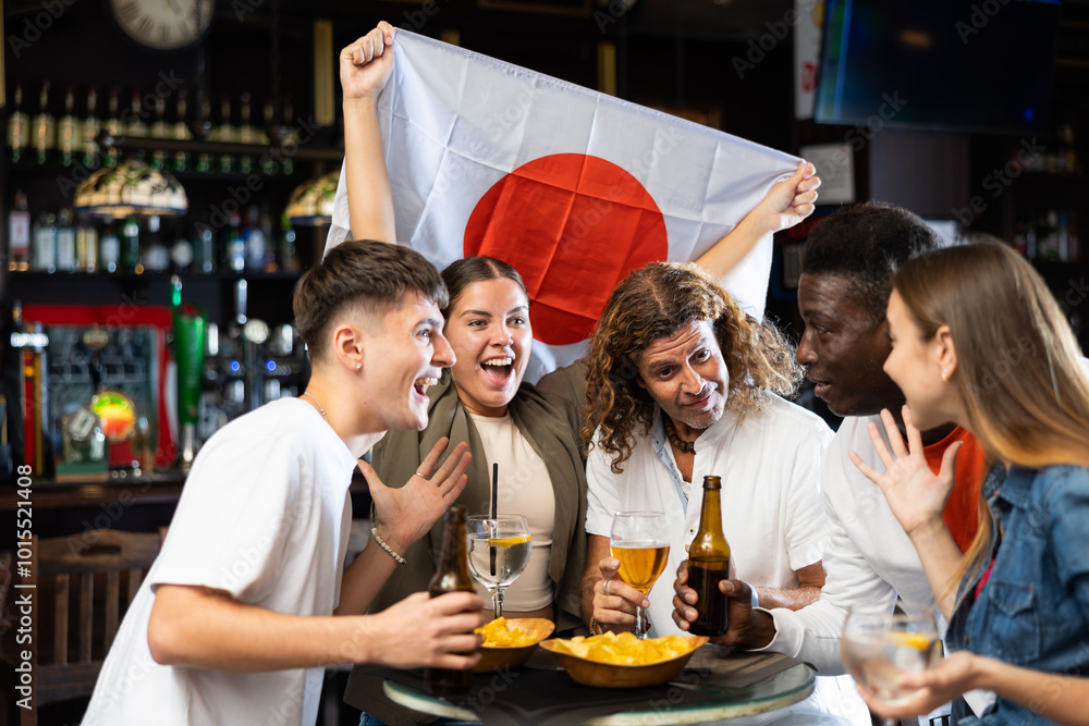 Naklejka premium Diverse men and women supporting Japan sports team in pub together. Happy group of friends raising Japan flag.