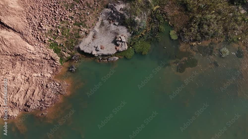 Aerial view of a quarry with intersecting dirt roads, gravel piles, and water ponds in an open mining area. Aerial view of a quarry with intersecting dirt roads, gravel piles, and water ponds in an open mining area.