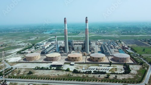 Aerial view of pipes of thermal power plant. City thermal power station among urban areas, top view. Aerial cinematic position gas turbine plant station. Tall Chimneys in Muzaffargarh, Multan Pakistan photo