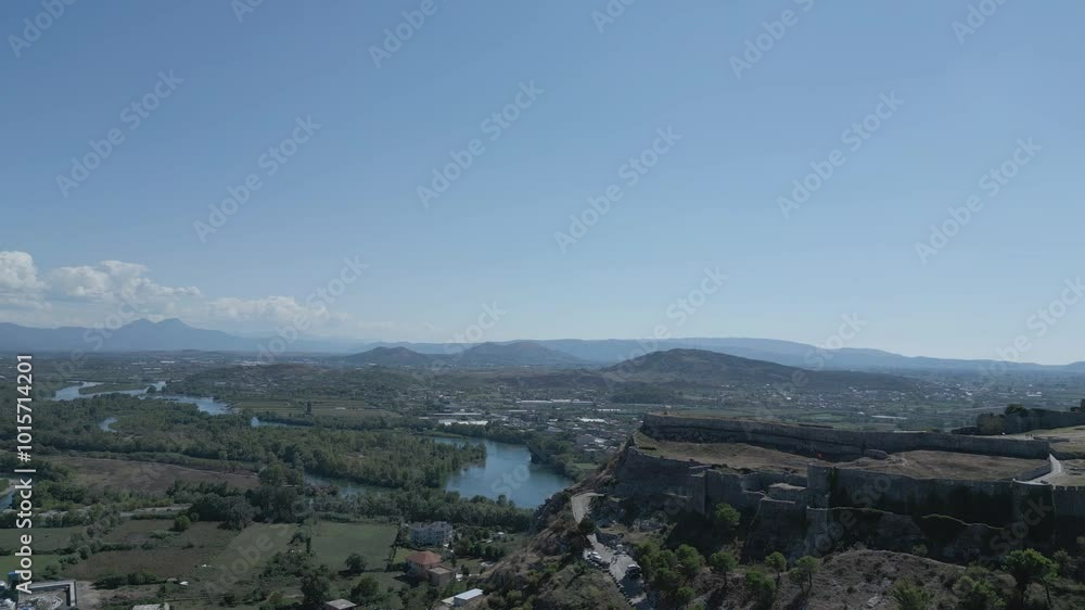 A drone video showcases Rozafa Castle in Albania, perched atop a hill with panoramic views of Shkodra city, winding rivers, lush landscapes, and ancient stone walls against a backdrop of mountains. A drone video showcases Rozafa Castle in Albania, perched atop a hill with panoramic views of Shkodra city, winding rivers, lush landscapes, and ancient stone walls against a backdrop of mountains.