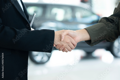 Close Up Of Businesswoman Shaking Hands With Saleswoman At Car Showroom
