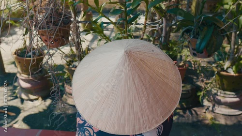 Asian person in conical hat working in the garden. photo