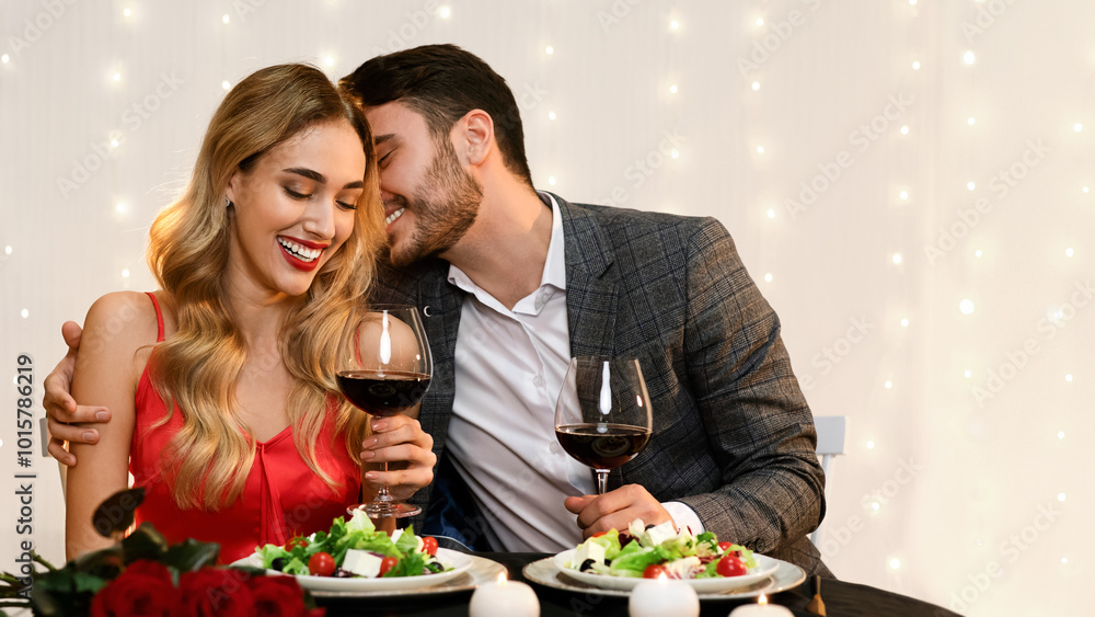 Loving Pair Dining In Restaurant, Having Romantic Date, Celebrating Valentine's Day Together. Man Whispering Into Girlfriend's Ear, Copy Space Loving Pair Dining In Restaurant, Having Romantic Date, Celebrating Valentine's Day Together. Man Whispering Into Girlfriend's Ear, Copy Space