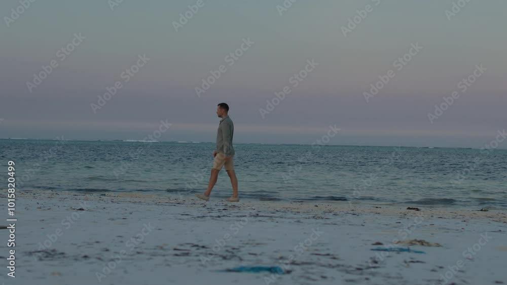 Thoughtful lonely man walk along the tropical beach in silence, contemplating the sunset. Thoughtful lonely man walk along the tropical beach in silence, contemplating the sunset.
