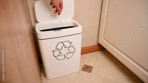 Two batteries are thrown into a bin with a recycling sign