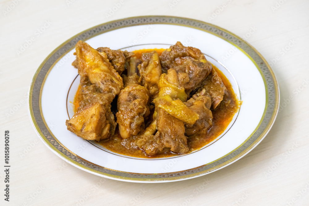 Delicious homemade chicken curry or chicken bhuna on a white plate, placed on light wooden surface. Authentic Bengali cuisine cooked deshi chicken meat. Delicious homemade chicken curry or chicken bhuna on a white plate, placed on light wooden surface. Authentic Bengali cuisine cooked deshi chicken meat.