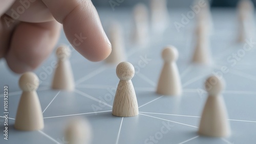 A hand reaches toward a central wooden pawn on a network of other pawns, symbolizing connection or leadership in a strategic game. photo