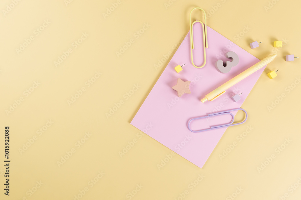 Top view of pink notebook on yellow background. Paperclips, pen, number, shape and pins. School, office wallpaper. Flat lay, copy space. Top view of pink notebook on yellow background. Paperclips, pen, number, shape and pins. School, office wallpaper. Flat lay, copy space.