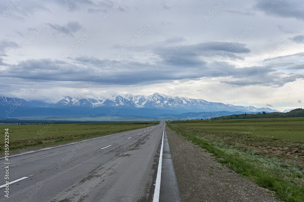 Road in the steppe with snow-capped mountains in the background Road in the steppe with snow-capped mountains in the background