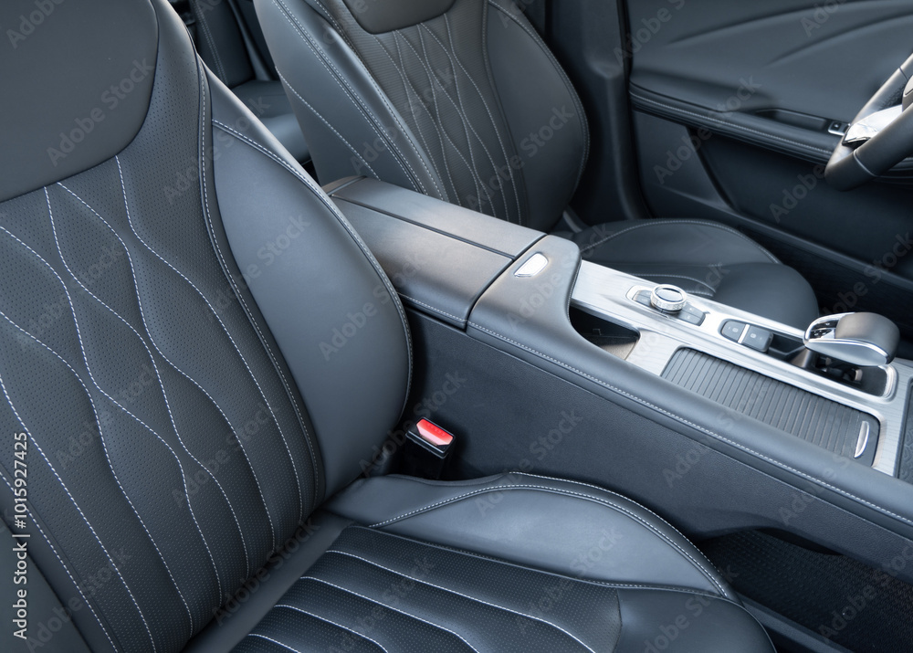 Obraz premium Modern luxury car black leather interior. Part of black leather car seat details with white stitching. Interior of prestige car. Comfortable perforated leather seats. Perforated leather..