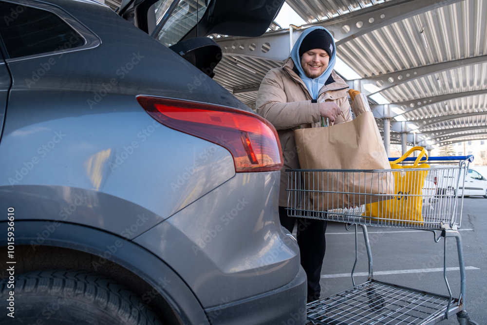 Man Loading Groceries into Car Trunk