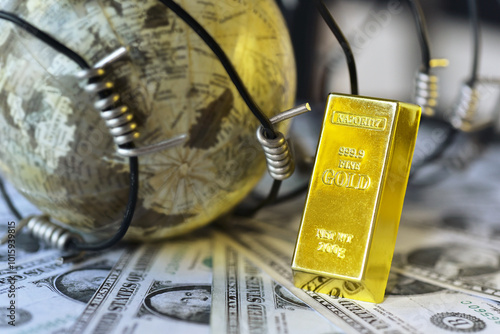 Gold bar lean against war barbed wire on USD bills beside blur globe . Gold is hard commodity goods, risk asset, tangible value that used to be gold reserve, save assets during war and economic crisis photo