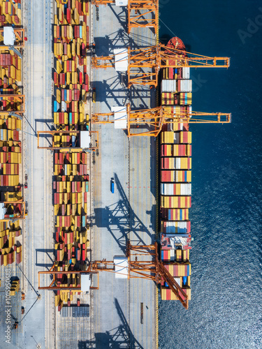 Aerial top view of an industrial container cargo ship terminal with unloading activity of cranes and trucks for the shipping business photo