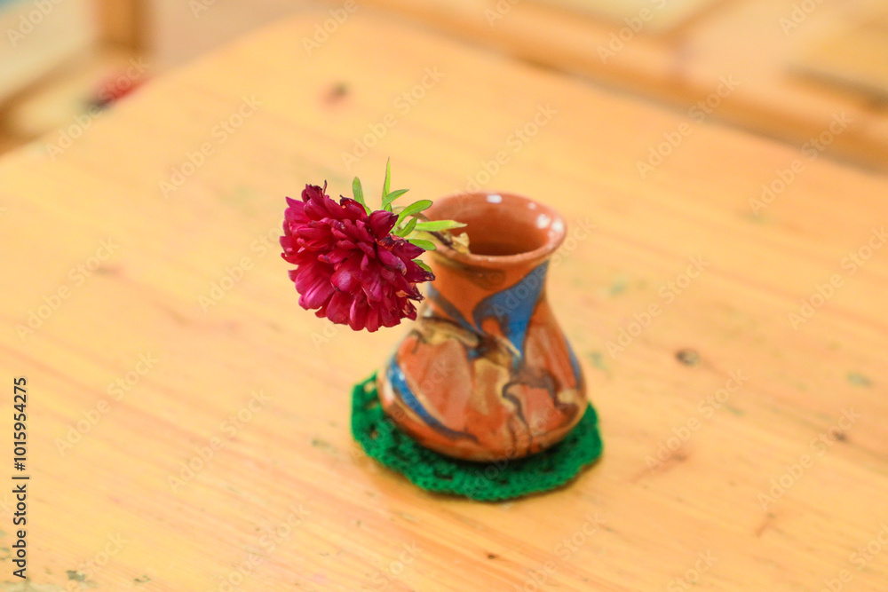 Small ceramic vase with a single flower on a Montessori classroom table Small ceramic vase with a single flower on a Montessori classroom table