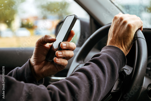 Male driver is driving car and texting on mobile phone