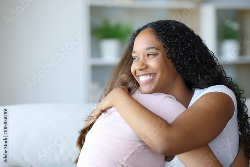 Happy black woman hugging her friend at home