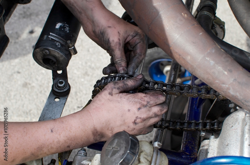 Hands of a boy racer who adjusts the chain on his sports car.