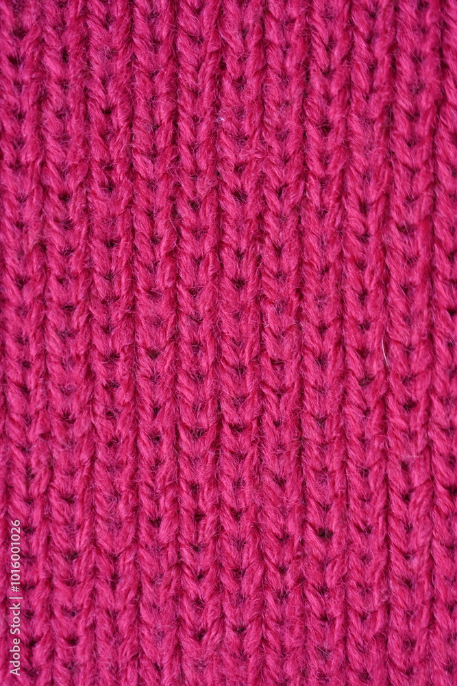 pink texture of knitted wool fabric as a background, smooth symmetrical lines of hand-knitted needlework pattern pink texture of knitted wool fabric as a background, smooth symmetrical lines of hand-knitted needlework pattern