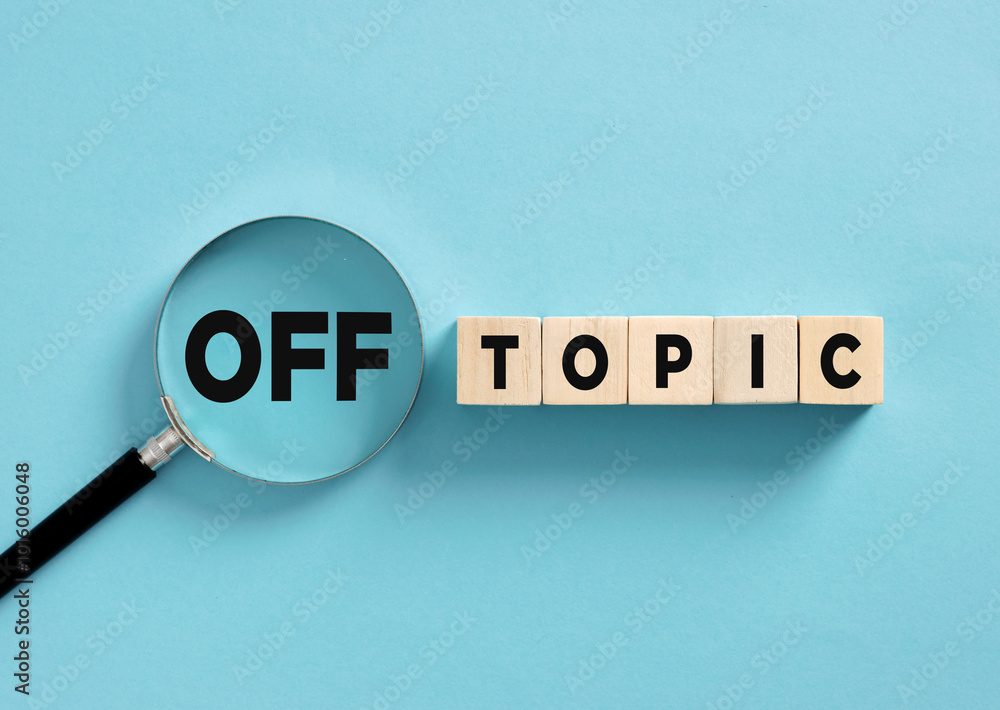 Magnifying glass is focusing on the word off topic formed by wooden blocks Magnifying glass is focusing on the word off topic formed by wooden blocks