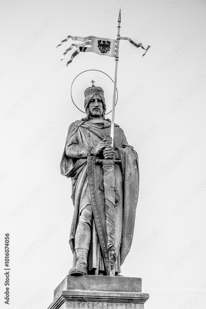 Obraz premium The statue of Saint Wenceslaus towers in Stara Boleslav, Czechia, prominently displaying the saint holding a flag atop a pedestal, symbolizing his historical significance to the region.