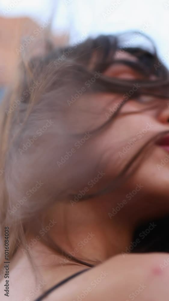 A fashion model girl posing on the street, wind in her face, enjoying the beauty industry with silver earrings and jewelry on her hands, a brunette with beautiful lips, femininity in the city streets,