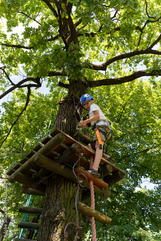 Teenage walk on a rope trail in an adventure rope park. Child in forest adventure park. Kids climb on high rope trail. Teenage walk on a rope trail in an adventure rope park. Child in forest adventure park. Kids climb on high rope trail.