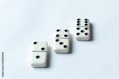 The game of dominoes is a table game involving rectangular pieces with dots that represent numbers. The objective is to match tiles with matching numbers. Photo with white background.