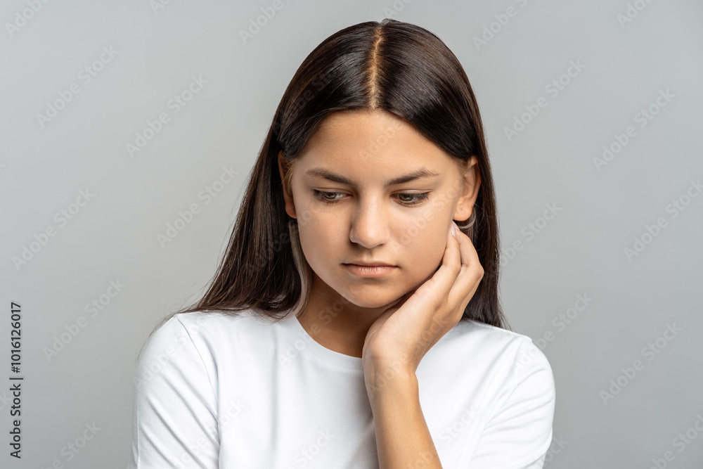 Embarrassed teenager girl avoids looking up, show shyness and discomfort in gray isolated studio. School girl with downcast eyes feel insecurity, social anxiety, vulnerability, pressures and judgment Embarrassed teenager girl avoids looking up, show shyness and discomfort in gray isolated studio. School girl with downcast eyes feel insecurity, social anxiety, vulnerability, pressures and judgment