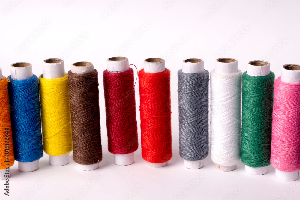 Colorful sewing thread set and needles isolated on background.